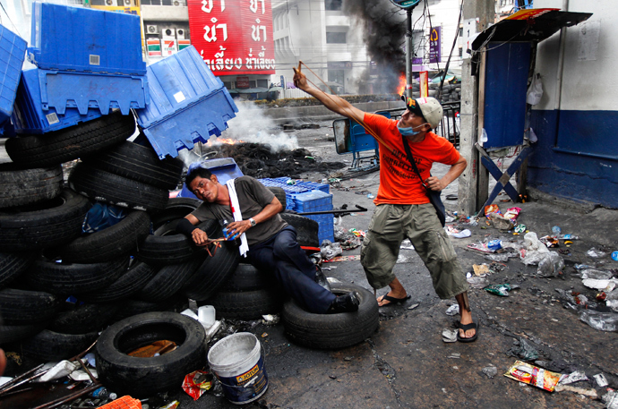 An anti-government "red shirt" supporter aims his slingshot at army soldiers, as his intoxicated comrade lies against a barricade made out of tires, at Rama IV Street in Bangkok May 16, 2010. (Reuters / Jerry Lampen)