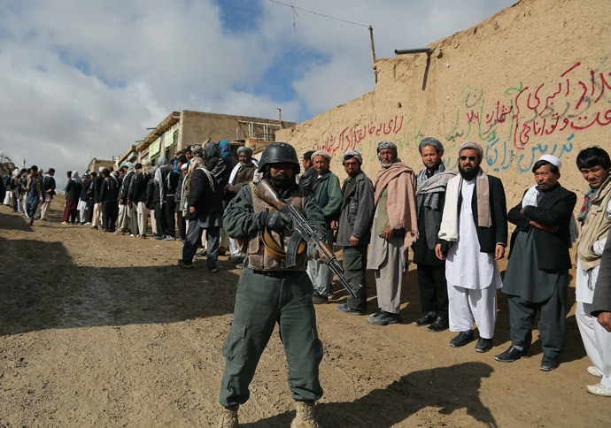 An Afghan policeman keeps watch as Afghan voters line up to vote at a local polling station in Ghazni on April 5, 2014. (AFP Photo / Rahmatullah Alizadah)