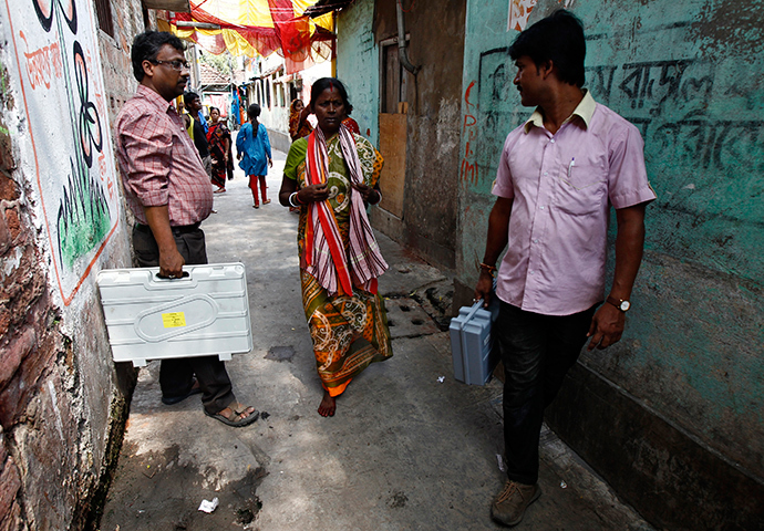 Polling officials carry electronic voting machines in an alley to demonstrate to residents how to use the machines during an awareness program at a red-light area in Kolkata May 6, 2014 (Reuters)