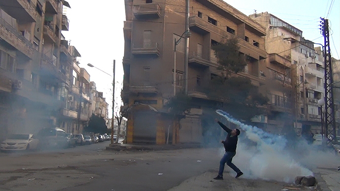A protester in the flahspoint central Syrian city of Homs throws a tear gas bomb back towards security forces, on December 27, 2011. (AFP photo)
