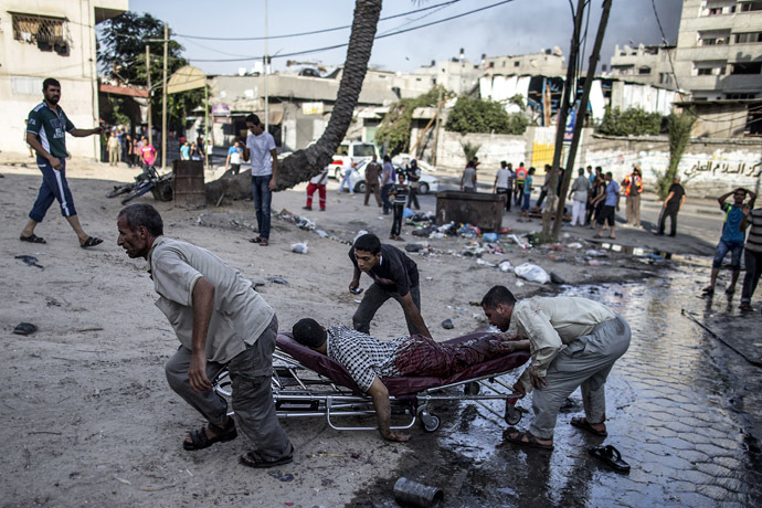 Palestinian men move the victim of an Israeli air strike on a market place to an ambulance in the Shejaiya neighbourhood near Gaza City on July 30, 2014. (AFP Photo)