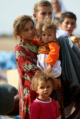 Displaced people from the minority Yazidi sect, who fled the violence in the Iraqi town of Sinjar, wait to board a bus to re-enter Iraq from Syria, at Nowruz refugee camp in Qamishli, northeastern Syria, August 17, 2014 (Reuters / Rodi Said)