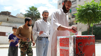 Syrian men pretend they are casting their votes during a mock election calling for the 