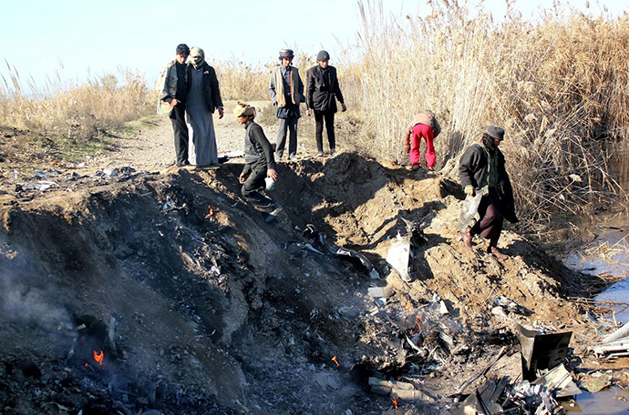 A picture taken on December 24, 2014 reportedly shows Islamic State group fighters collecting pieces from the remains of a Jordanian warplane from the US led coalition after it was shot down in Syria's Raqa region (AFP Photo / STR)