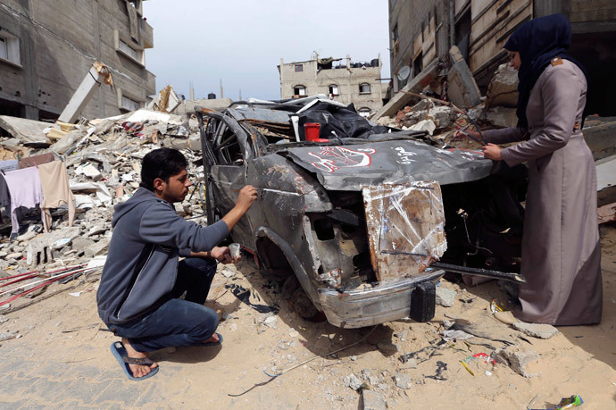 Palestinian artists paint on the remains of car that witnesses said was destroyed by Israeli shelling during a 50-day war last summer, in Rafah in the southern Gaza Strip February 24, 2015. (Reuters / Ibraheem Abu Mustafa)