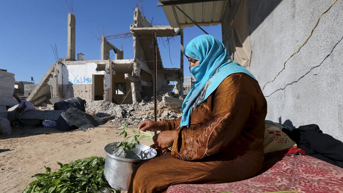 A Palestinian woman prepares food near the wreckage of her house that witnesses said was destroyed by Israeli shelling during a 50-day war last summer, in Khan Younis in the southern Gaza Strip June 22, 2015. (Reuters/Ibraheem Abu Mustafa)