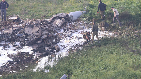 Les forces de sécurité israéliennes marchent près des restes du F-16 israélien abattu, près du village israélien de Harduf, le 10 février