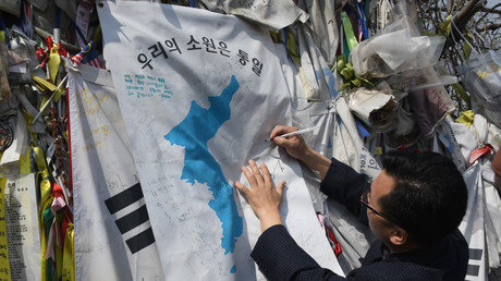 Un homme &eacute;crit sur un drapeau de l'unification accroch&eacute; &agrave; la cl&ocirc;ture s&eacute;parant les deux Cor&eacute;es, &agrave; Paju, le 26 avril