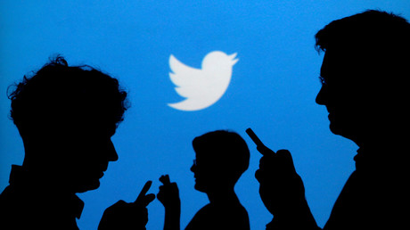 Silhouettes d'internautes sur un fond représentant le logo de Twitter (Image d'illustration).