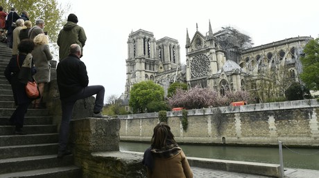 Les passants contemplent les ruines depuis les quais de la Seine le 16 avril au matin.