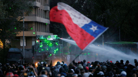 Des manifestants hissent le drapeau du Chili devant un canon à eau, lors d'une manifestation contre le gouvernement à Santiago, capitale du pays, le 10 janvier 2020.