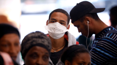 Un homme porte un masque pour lutter contre la propagation de la maladie, dans un dépôt de bus au Cap, en Afrique du Sud, le 18 mars 2020