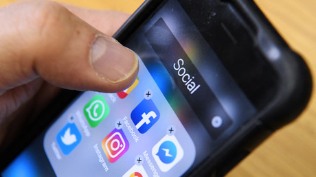 Un homme tient un smartphone avec les icônes des applications de réseaux sociaux Facebook, Instagram et Twitter, le 23 mars 2018 (illustration).