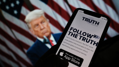 La page internet de TRUTH Social sur un smartphone, devant une image de Donald Trump,  à Los Angeles, le 21 octobre 2021.