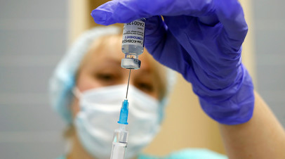 Медработник набирает вакцину в шприц