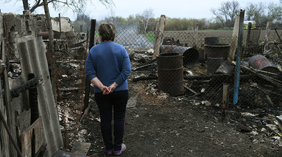 Женщина во дворе жилого дома, пострадавшего в результате обстрела. ЛНР